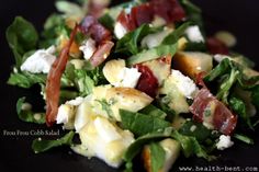 a salad with bacon, cheese and lettuce in it on a black plate