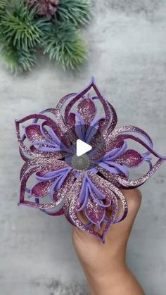 someone is holding a purple and silver flower