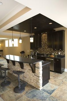 a kitchen with black cabinets and stone counter tops