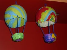 two colorful hot air balloons are hanging on the wall