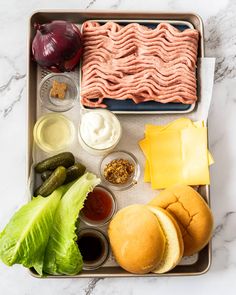 a tray with meat, cheese, lettuce, pickles and other food items