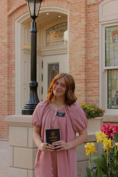 a woman standing in front of a lamp post holding a book