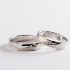 two white gold wedding rings with diamonds on each one, set against a plain background