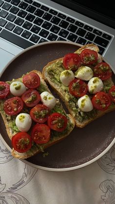 two slices of toast with tomatoes and mozzarella on top, next to a laptop