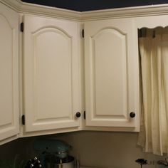 a kitchen with white cupboards and a pot on the stove top in front of it