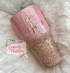 a pink glitter tumbler sitting on top of a white blanket