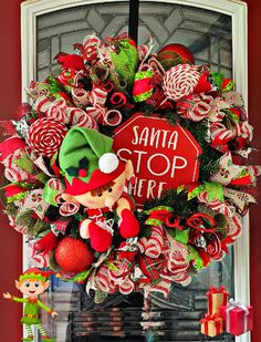 a christmas wreath hanging on the front door with santa's stop sign and candy canes