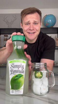 a man holding up a bottle of green juice