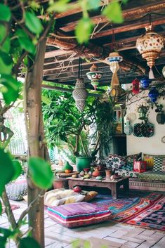 a living room with lots of plants on the wall and rugs hanging from the ceiling