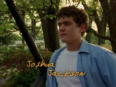 a young man standing in front of trees with the words joshua jackson written on it