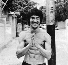 a shirtless man standing in front of a pole with his hands together and smiling