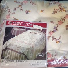 the bed cover is white with pink flowers on it and has an english manor design