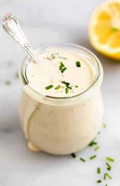 a glass jar filled with cream sauce next to a lemon