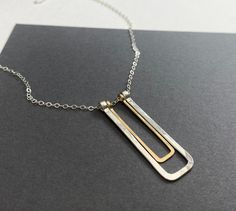 This necklace features a geometric pendant made with heavy gauge sterling silver wire shaped into a narrow rectangle that's been hammered flat with a smaller narrow gold rectangle made from 14k gold filled wire. It hangs on lightweight sterling cable chain and finished with a lobster clasp.  The pendant measures about 1.5" long and about 1/2" wide. Various necklace lengths are available. All jewelry is sent inside a sturdy jewelry gift box. Modern Gold Bar Necklace With Rectangular Pendant, Rectangular Silver Necklaces For Everyday Use, Minimalist Hammered Jewelry With Rectangular Pendant, Silver Rectangular Necklace For Everyday, Minimalist Hammered Rectangular Pendant Jewelry, Everyday Hammered Rectangular Jewelry, Everyday Silver Rectangular Necklace, Modern Sterling Silver Bar Necklace, Minimalist Rectangular Necklace For Everyday Use