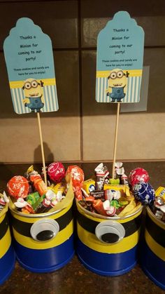 minion birthday party favors in blue and yellow buckets with candy candies on top