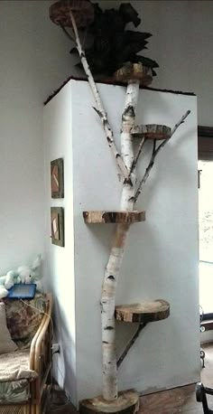 a white refrigerator sitting in a living room next to a tree branch decoration on the wall