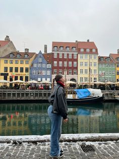 a woman standing on the side of a river next to buildings