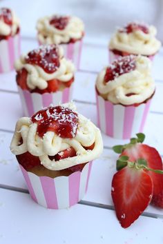 strawberry cupcakes with cream cheese frosting and strawberries on the side, ready to be eaten