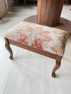 a wooden bench with an upholstered seat and floral fabric on the backrest