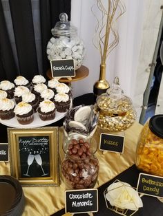 a table topped with lots of cupcakes and desserts next to framed pictures