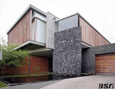 a modern house with two garages and brick driveway