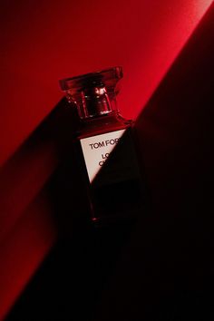 a bottle of tom ford l'oeuvret on a red wall in the dark