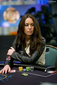 a woman sitting at a poker table with her arms crossed