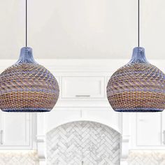 two pendant lights hanging from a kitchen ceiling over a stove top oven in a white kitchen