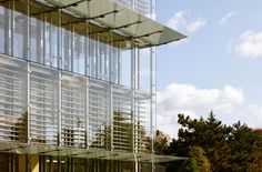 a tall glass building sitting on top of a lush green field