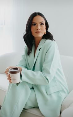 a woman sitting on a couch holding a cup of coffee