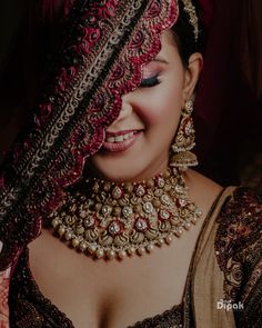 a woman in a red and gold outfit with jewelry on her head, smiling at the camera