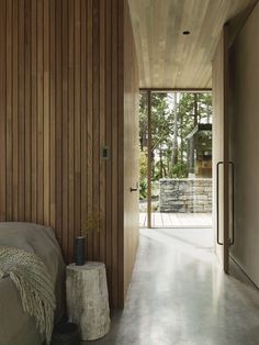 a bedroom with wooden walls and flooring next to a door leading to a patio