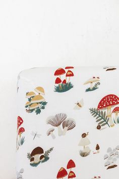 an upholstered suitcase with mushrooms and leaves printed on the front, sitting against a white wall