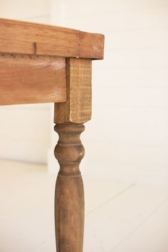 an old wooden bench with wood slats on the top and bottom edge, in front of a white wall