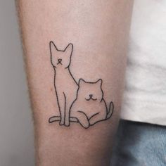 a small cat and dog tattoo on the left inner arm, which is drawn in black ink