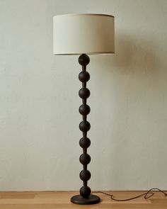 a lamp that is on top of a wooden table next to a wall and floor