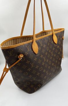 The Neverfull MM tote unites timeless design with heritage details. Made from supple Monogram canvas with natural cowhide trim, it is roomy yet not bulky, with side laces that cinch for a sleek allure or loosen for a casual look. Slim, comfortable handles slip easily over the shoulder or arm. The Louis Vuitton monogram is a print that is carefully crafted from durable, brown canvas, Louis Vuitton's embossed, classic interwoven "LV" has remained the brand's signature since 1896. Louis Vuitton’s coated canvas is one of the most durable materials in the game. Originally created for use on the brand’s travel trunks. The material’s durability shouldn’t come as much of a surprise, considering the travel trunks back in the day needed to withstand a lot of wear and tear. It’s not only resistant to Louise Vuitton, Louis Vuitton Neverfull Pm, Louis Vuitton Dust Bag, Neverfull Mm Monogram, Louis Vuitton Totes, Louis Vuitton Neverfull Mm, Neverfull Mm, Brown Canvas, Louis Vuitton Bag Neverfull