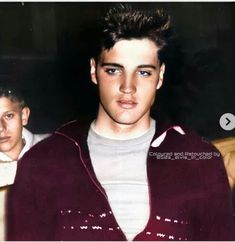 an old photo of a young man in a maroon jacket and white t - shirt