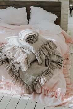 an unmade bed with pink ruffled sheets and blankets on top of the bed