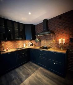 a kitchen with black cabinets and wooden floors is lit up by candles on the counter