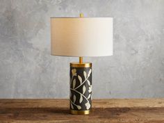 a black and gold lamp on a table with a white lampshade next to it