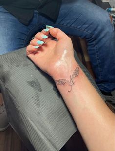 a woman's arm with a small tattoo on her left wrist and an angel wing