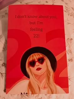 a red book with a drawing of a blonde woman wearing sunglasses and a black hat