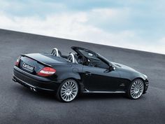 a black convertible car parked on top of a parking lot next to a blue sky