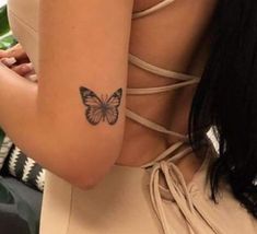 a woman's arm with a butterfly tattoo on the back of her left arm