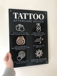 a person holding up a sign that says tattoo aftercare advice on the side of a wall