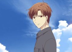 a young man with brown hair standing in front of a blue sky and white clouds