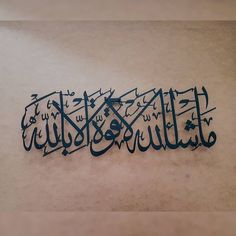 an arabic calligraphy is displayed on the floor in front of a white wall with black writing