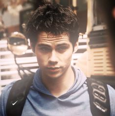 a man with a backpack standing in front of a building and looking at the camera