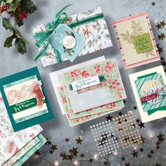 christmas cards and envelopes on a table next to some holly garland, star shaped decorations